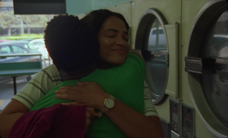 A man and woman smiling and hugging inside a laundromat