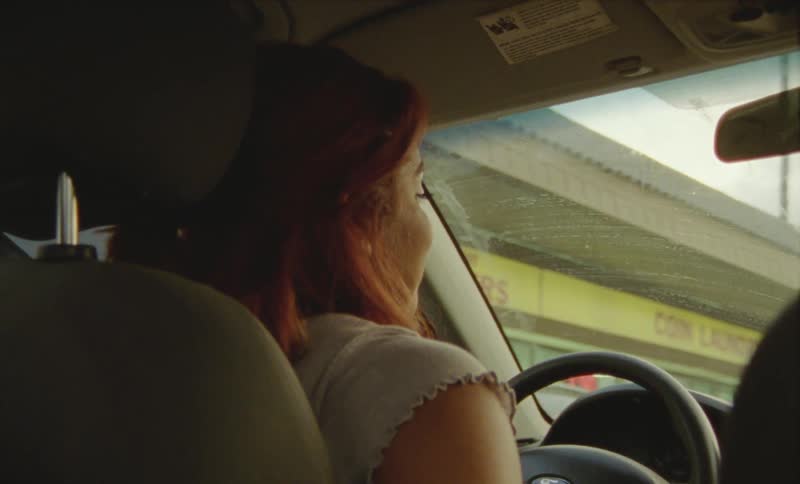 Happy woman talking to a passenger while driving a car in the city