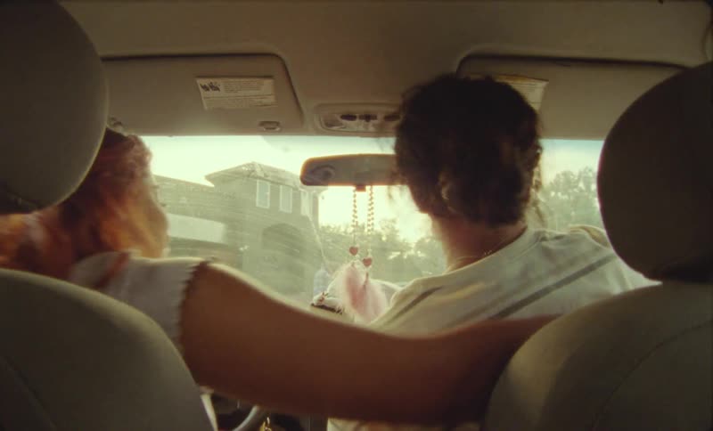 Young woman hugs a friend before getting out of a car parked in the city