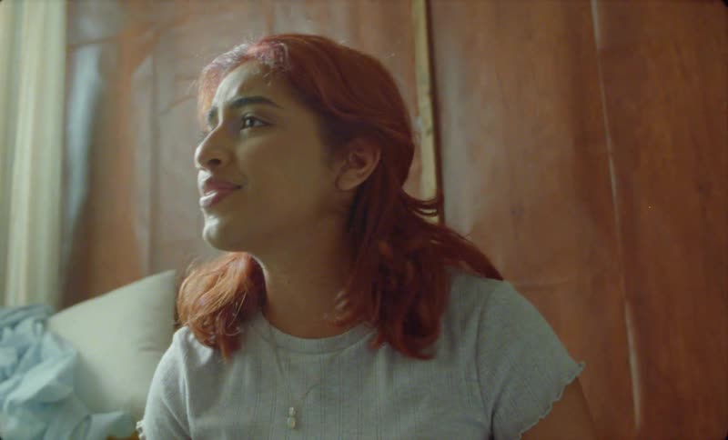 Woman with red hair and gray shirt folds clothes and talking person in room