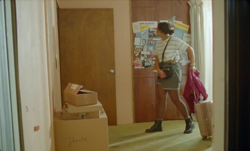 There is a young hispanic woman that is walking inside with her luggage