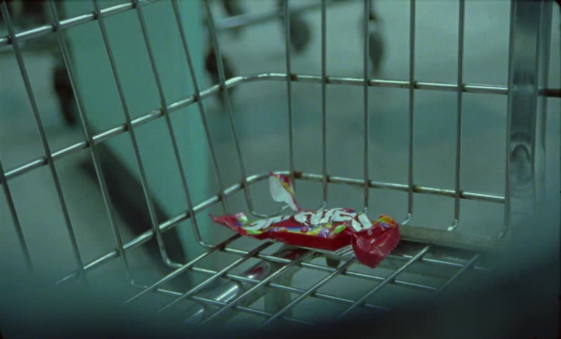 An empty candy wrapper sits in a grocery cart in a store