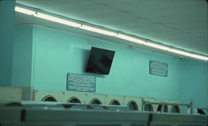 Black screen of a television screen hanging from the wall on an empty laundromat