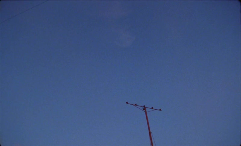 A jet airplane is flying over a utility pole