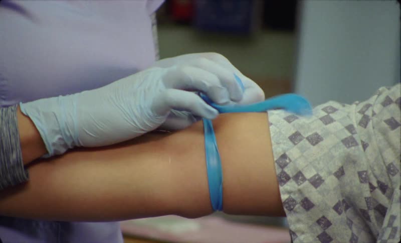 Young nurse prepares a patient arm to take a blood sample in the hospital