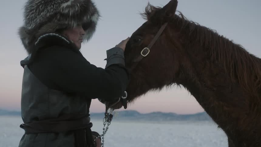 A man pets his horse on a cloudy day