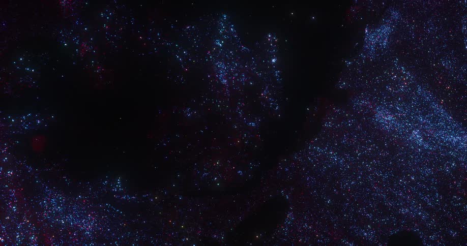 Blue and purple glitter sparkles as it flows against a dark background