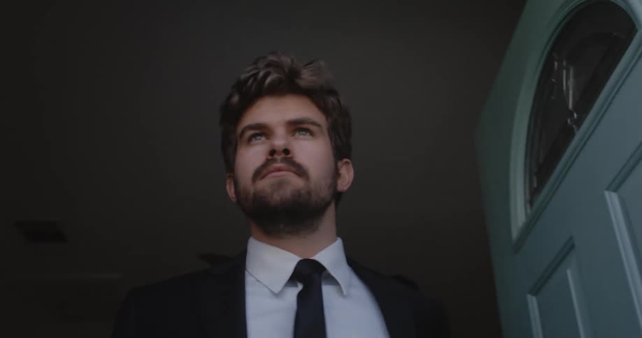 Man with beard and suit walks out the door