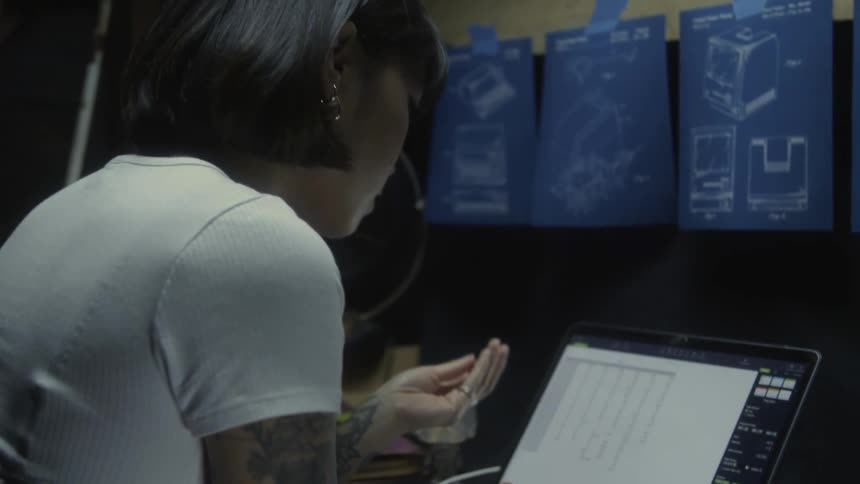 Woman with bob haircut sitting at desk uses laptop in room