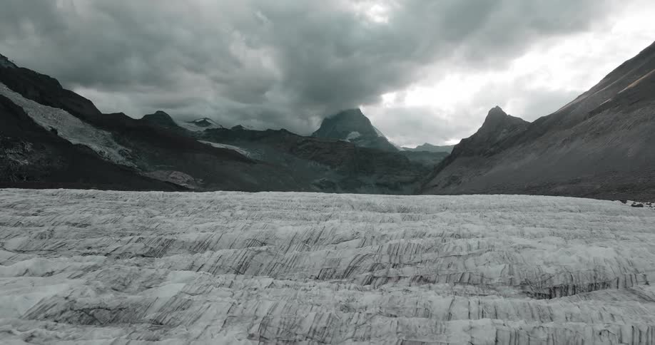 Dense clouds move over a snowy field and mountain range