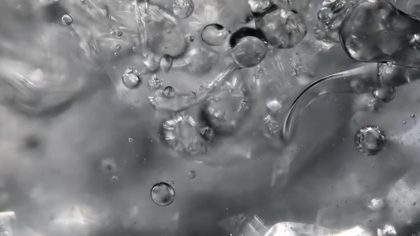 Air bubbles rise to the surface of a clear liquid
