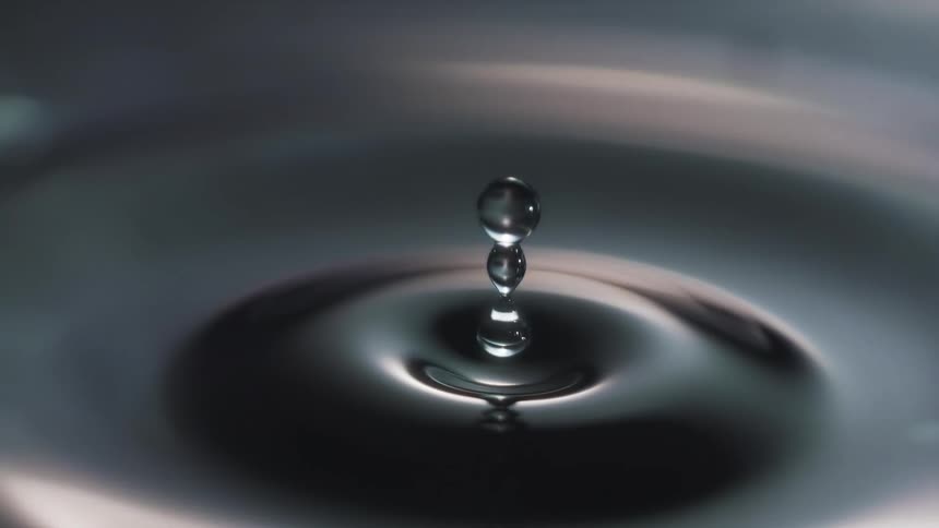 Round water droplets fall into the water and splash and ripple across the surface