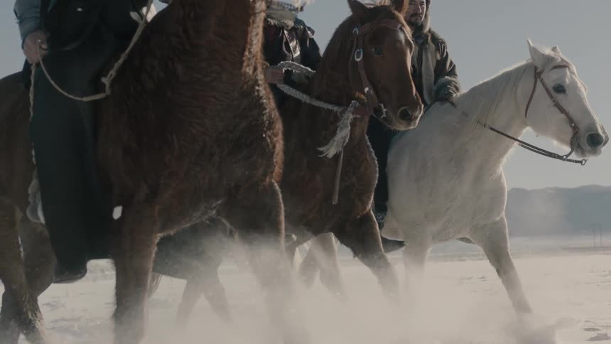Three people ride horses on a snow field