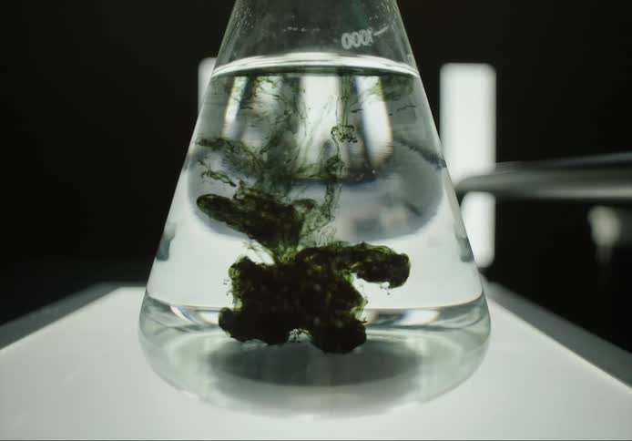 Green liquid being added to a beaker of water