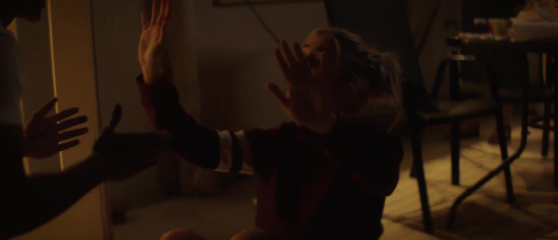 Friend helps a happy young teenage girl stand up from the living room floor and then hug