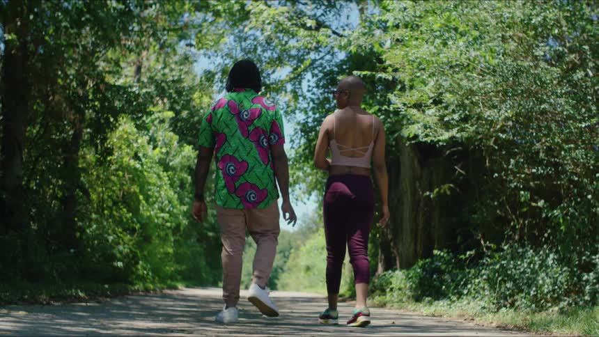 A man and woman going for a walk on a tree line path