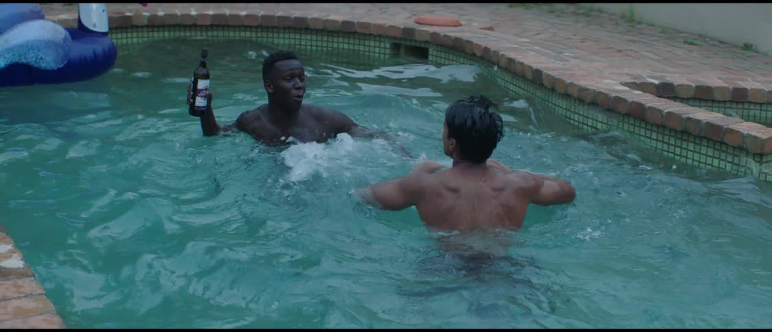 Two friends playfully fight for a wine bottle on a pool in the backyard