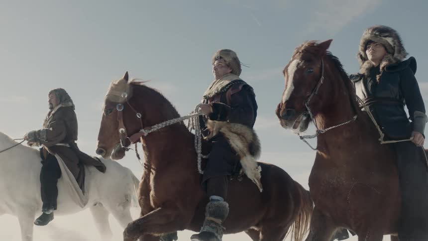 People riding horses across a snow covered pasture