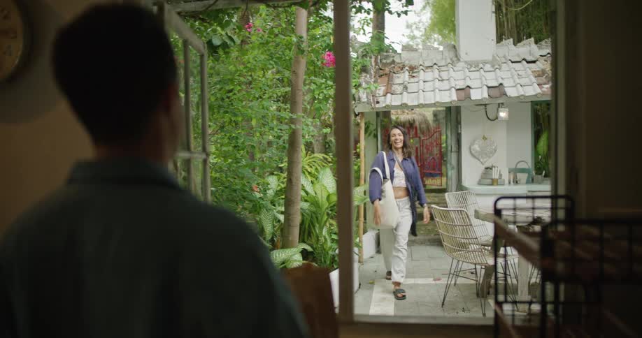 A woman enters a mans yard and waves
