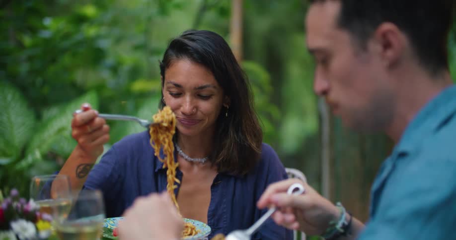A man and woman have dinner together in their yard