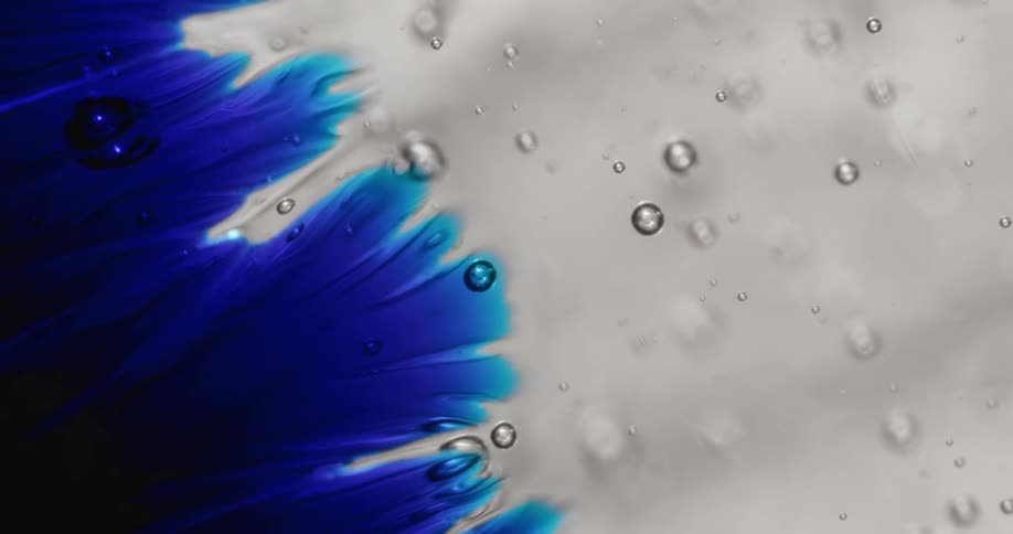 Small air bubbles form in a viscous blue and clear gel