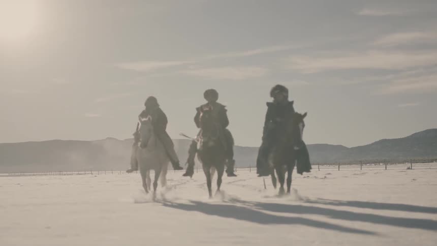 Three people on horseback ride on a cloudy day