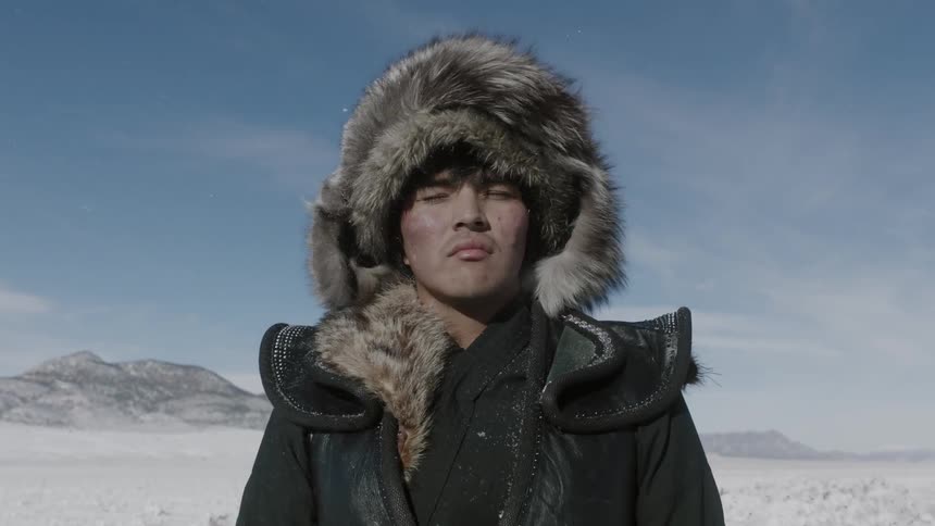 A man in a parka stands in a snow covered field