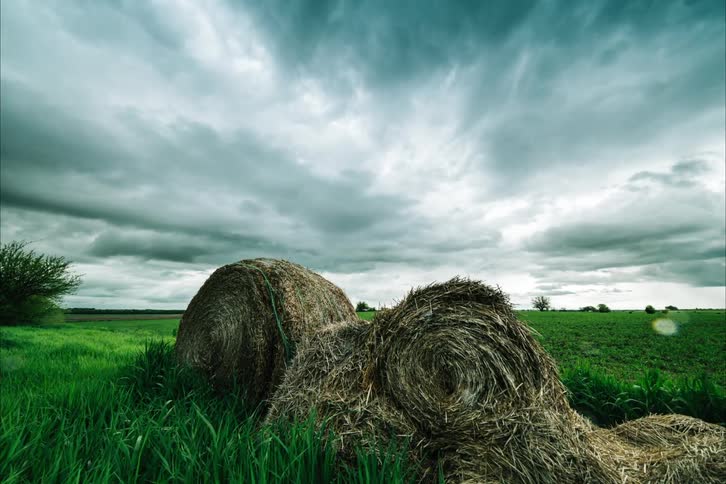 Storm clouds passing over a rural hay field during a summer rainstorm