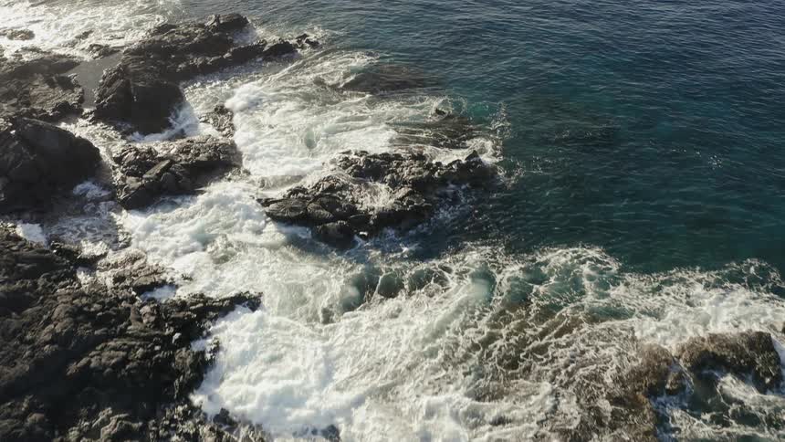 Large ocean waves crash onto rocks along the coast