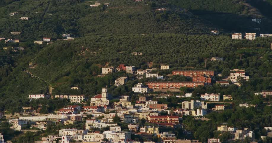 Buildings of a small town on the gentle slopes of a mountain covered in green lush vegetation
