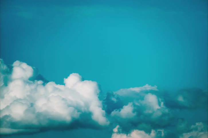 Cumulus clouds grow and move across the blue sky