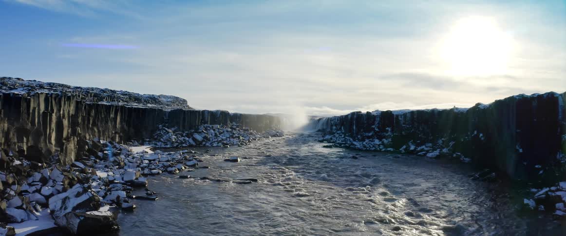 Camera pans over a river between cliffs in the winter
