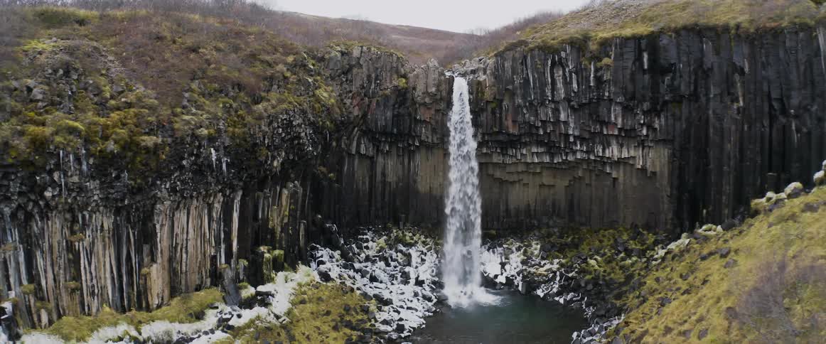 A waterfall flowing over a rocky cliff in winter