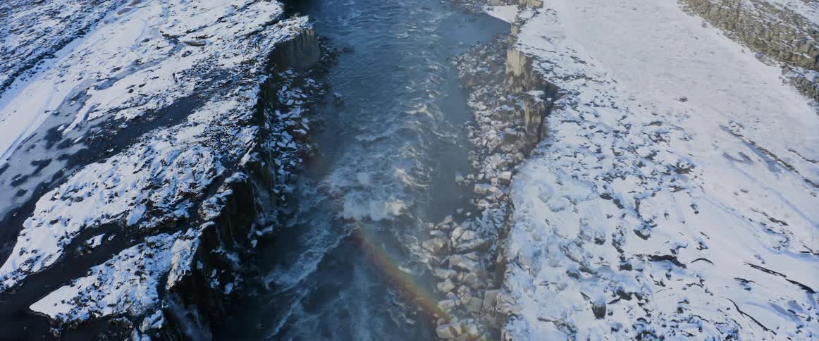 A river flowing through a snowy canyon in winter