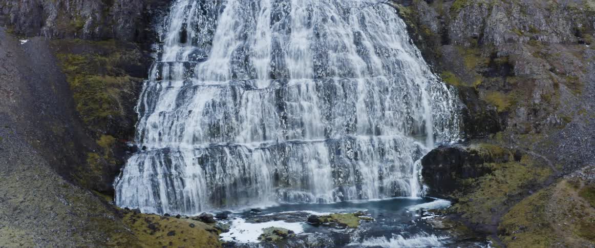 Water flows down the rocky stepped slope of a mountain in a waterfall