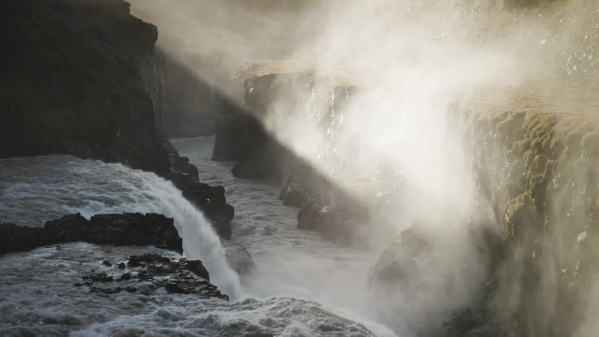 Water is falling over a cliff in a rocky canyon with steep walls
