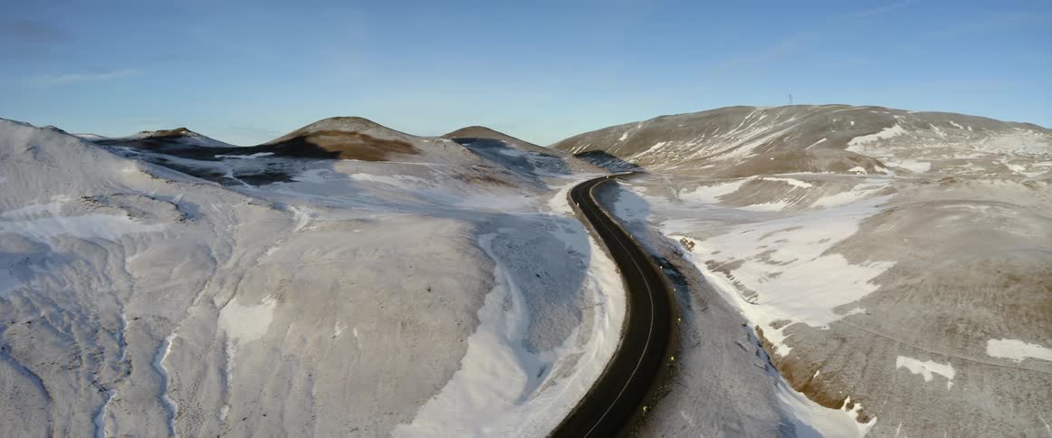 A paved road winding through snowy hills