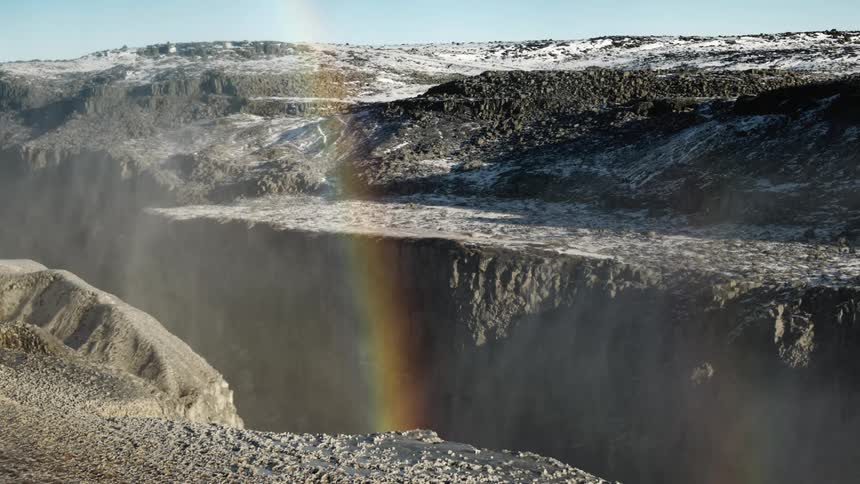 A rainbow forms over a snow dusted mountain