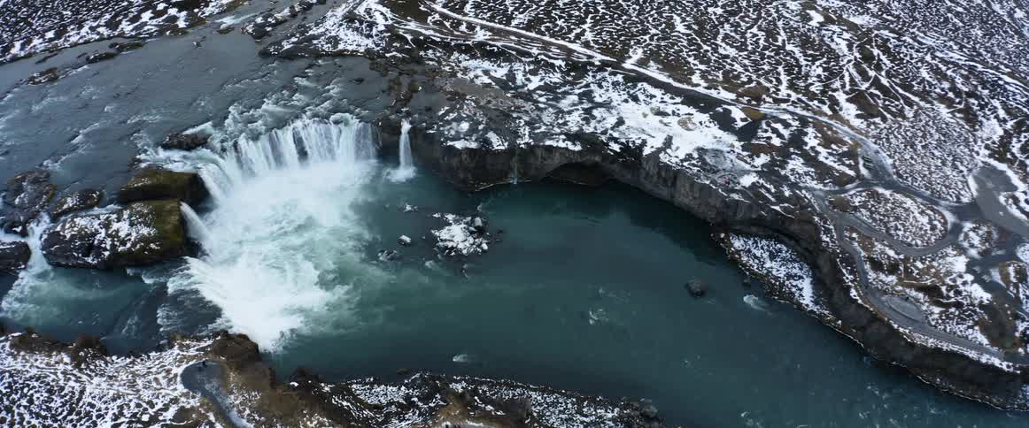 Camera slowly turns around over a large waterfall in the winter