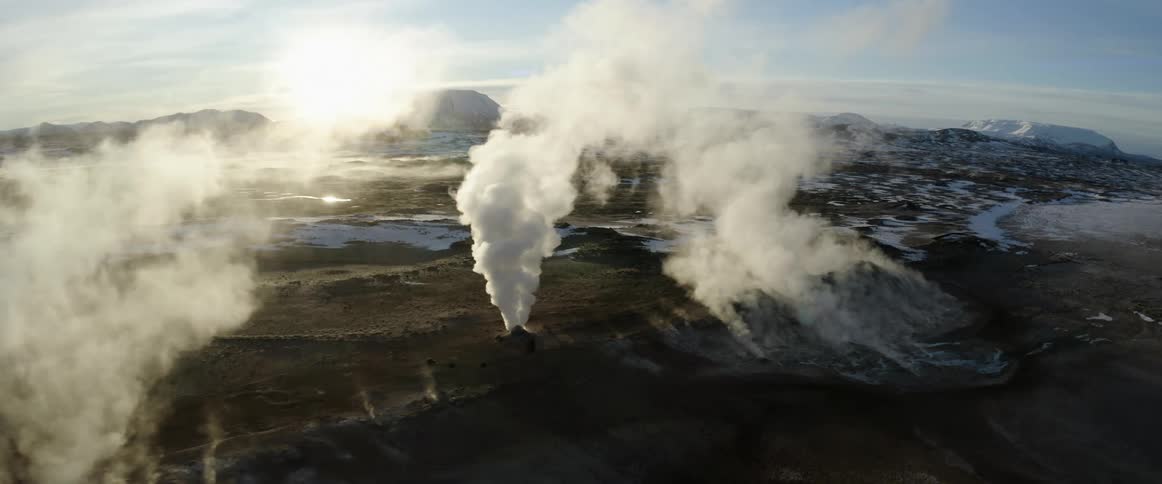 Wide aerial shot of smoke rising above plains with snow