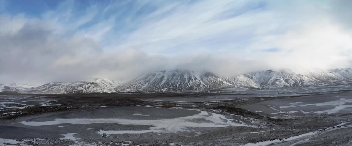 An aerial view of a snowy mountain landscape in the wilderness