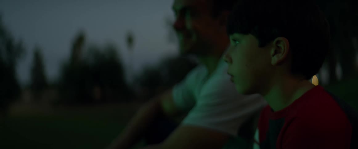 A man and his son are sitting outside watching flashing lights