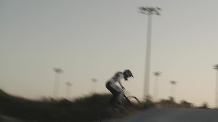 A cyclist on a bmx bike rides on a dirt track