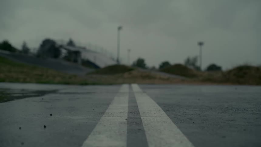 A bicycle travels across a double line painted on a wet road