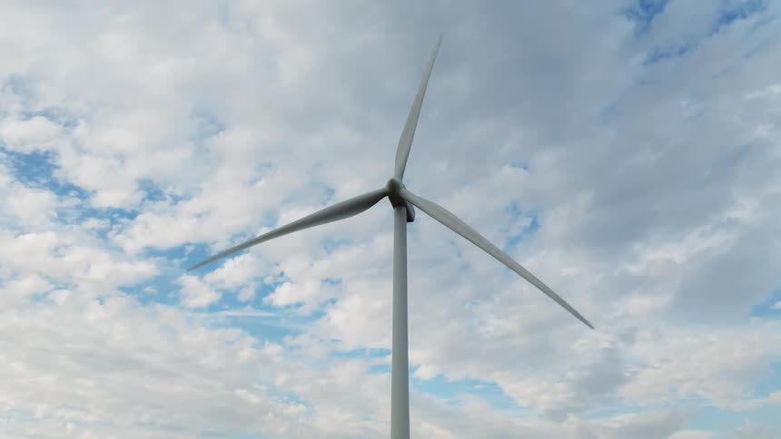 A wind turbine spins under a cloudy sky