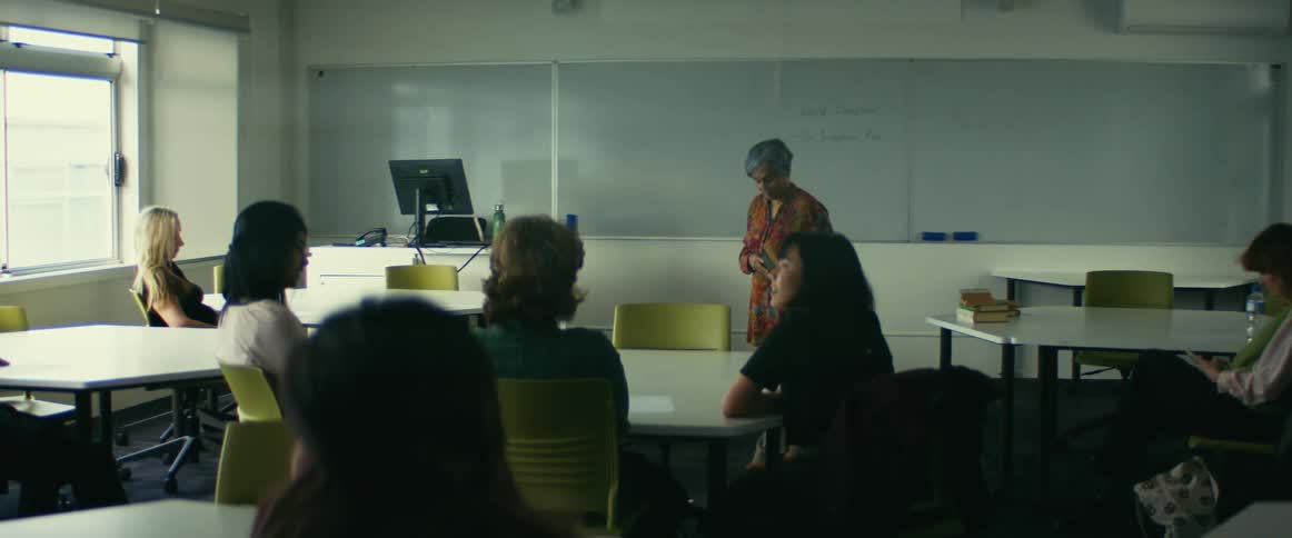 Students in a classroom are talking while a teacher is up front