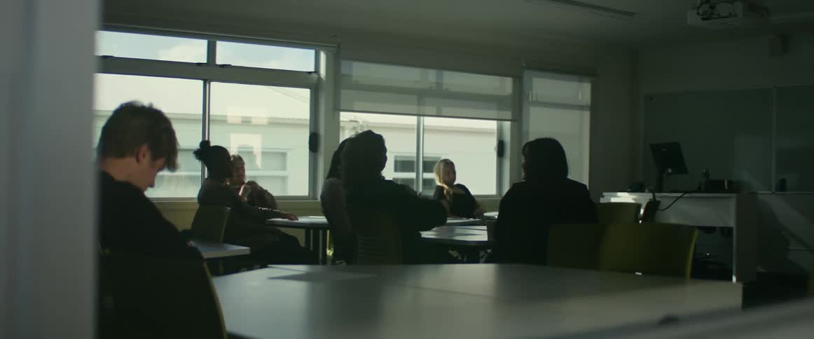 People sitting in a classroom talking and reading waiting for class to begin