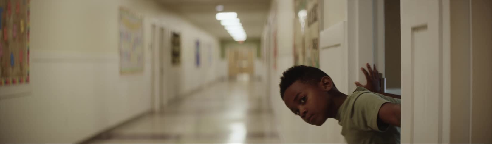 Child peeks out of the classroom door into the lonely school hallway