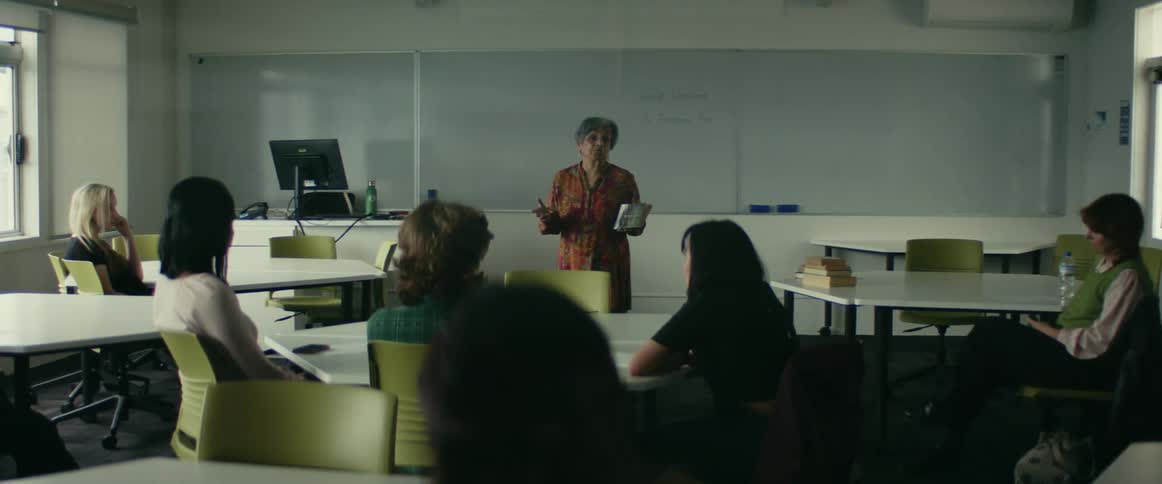 University teacher giving a lecture in front of students sitting on chairs in a classroom