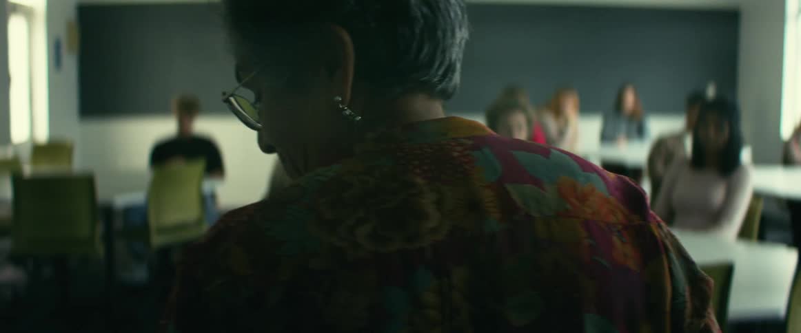 Camera pans past the back of a professor to reveal a classroom of students